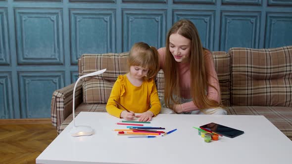 Cute Small Child Kid Daughter Learning Drawing Homework with Young Mother Home Distance Education