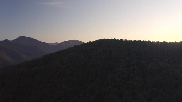 Sunset Light Shines on Green Valley Mountainous Landscape with Dense Forests