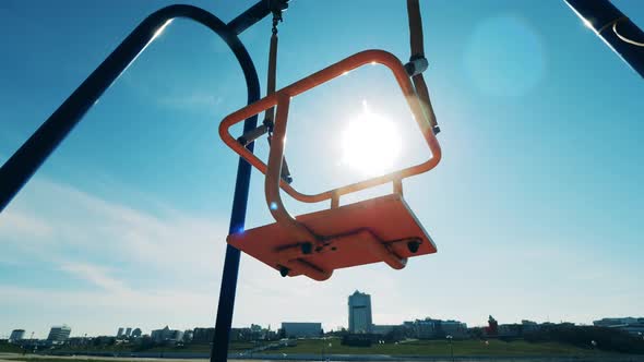 Empty Swings Are Swaying in Sunlight