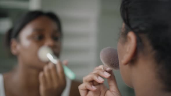 African-American woman applying make up blusher in the bathroom. Shot with RED helium camera in 4K.