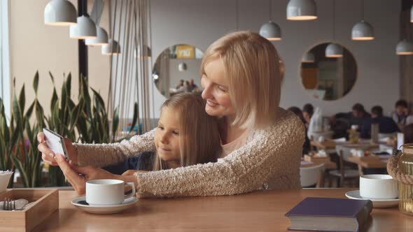 Woman Takes a Selfie with Her Daughter at the Cafe