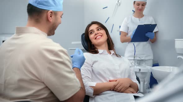 Dentistry Male Doctor and Female Smiling Patient Talking Discussing Tooth Treatment at Clinic