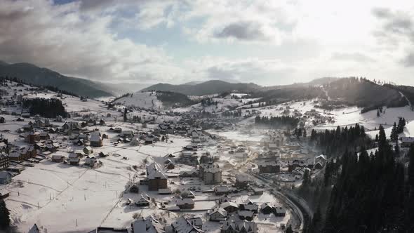 Aerial Footage of Small Mountain Village in Winter Time During Sunny Day with Epic Clouds