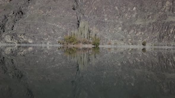 Aerial Flying Low Above Calm Khalti Lake Waters. Dolly Forward