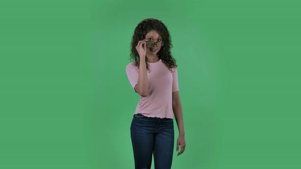 Portrait of Beautiful African American Young Woman Is Looking at Camera Fixing Her Glasses and Winks