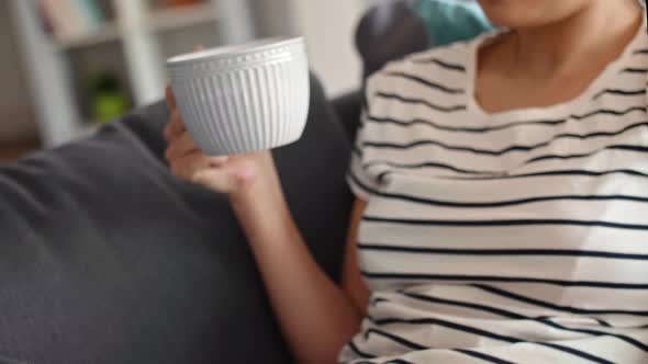 Tilt up video of woman using laptop and drinking something