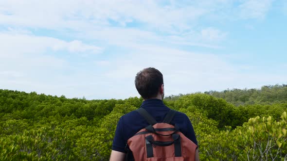 Tourist Man with Backpack Walking Among Green Treetops Adventure Travel Concept