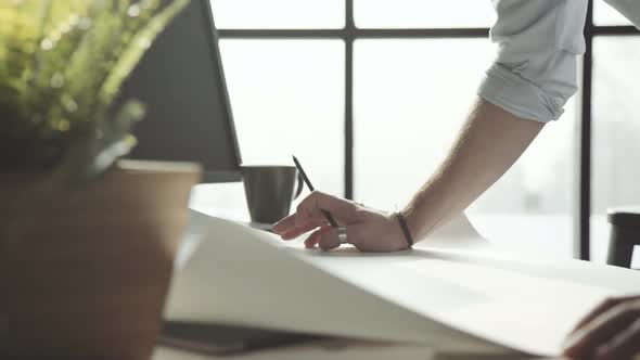 Large White Sheet with Drawings on the Table in Front of Architect