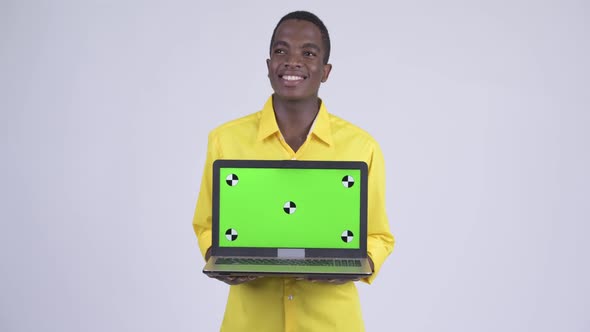 Young Happy African Businessman Thinking While Showing Laptop