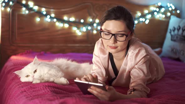 Pretty Woman Chatting Online at Home with Friends Together with Her Cat