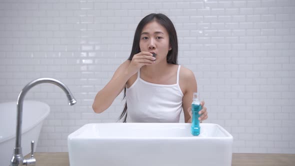 Daily routine concept. Young Asian woman gargling in the bathroom. 4k Resolution.
