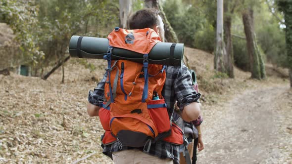 Couple of Hikers with Camping Backpacks Walking on Forest Path