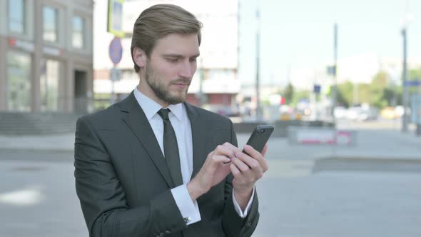 Businessman Browsing Internet on Smartphone Outdoor