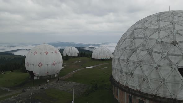 Aerial shot flying fast through and over abandoned Soviet radar station in Ukraine. Carpathian mount