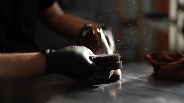 Close-up of man in black latex gloves cleaning shoe brush, brushing dust and dirt off with finger.