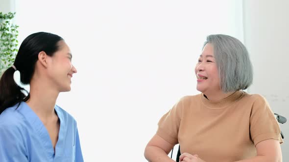 A young Asian nurse take care a disability senior while she sitting on a wheel chair.