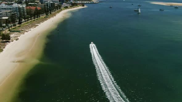 Speed boat racing parallel to the beach . Gold Coast Broadwater at  low tide.