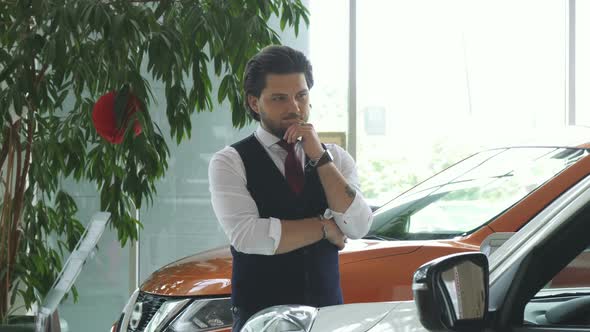 Young Handsome Businessman Examining Cars for Sale at the Dealership