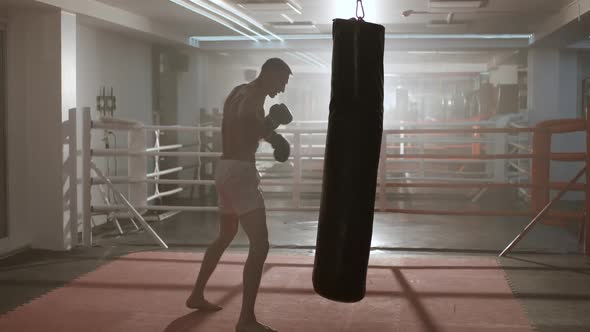 Kickboxing, Athletic Man Fighter Trains His Punches, Beats a Punching Bag, Training Day in the