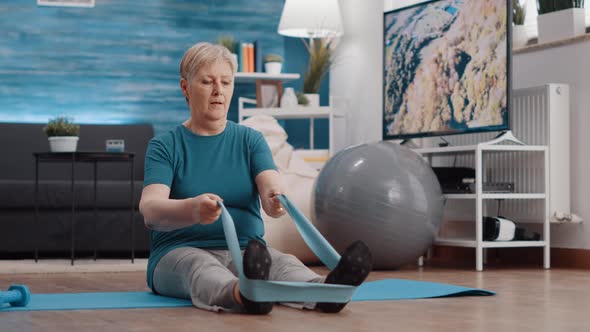 Aged Woman Using Resistance Band to Train Muscles