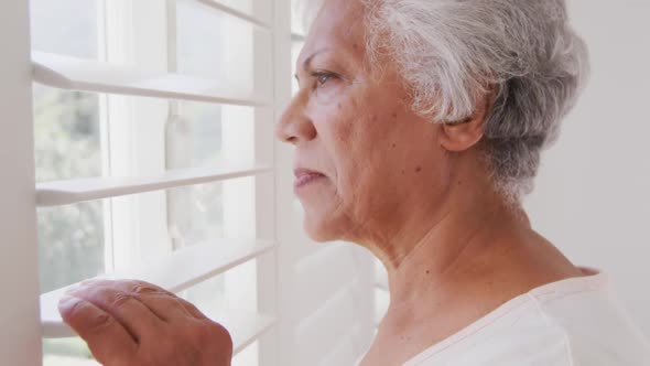 Senior African American woman looking at her window, at home