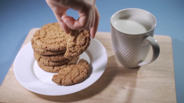 A Woman's Hand Dips Oatmeal Cookies in Milk