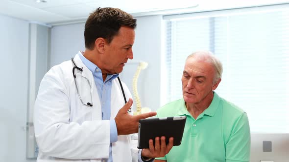 Doctor and senior patient discussing over digital tablet