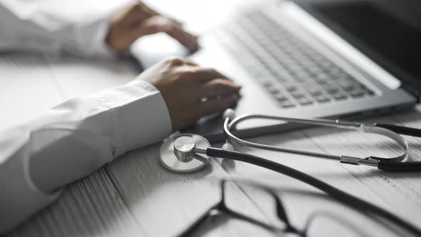 Close Up of a Doctor is Working and Typing on Laptop in a Clinic alt