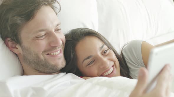 Couple using wireless device in bed