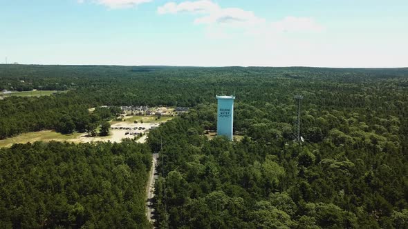 A water tower among green trees for the town of Bourne near the Cape Cod Canal.