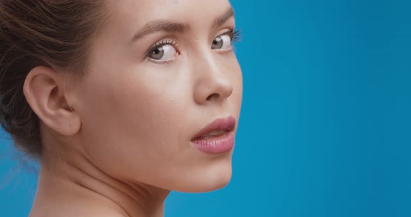 Beauty Portrait of Gorgeous Caucasian Lady Posing at Camera, Turning Face , Blue Studio Background