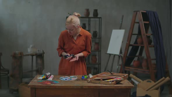 Female Artist Squeezing Paints on Color Palette in Studio