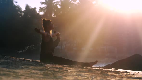 Young Exciting Woman in Black Tracksuit Sits on Sand Beach