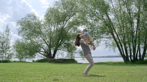 Happy Woman Lifting Baby in Air