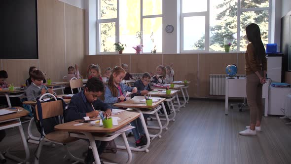 Little Pupils Drawing and Listening To Teacher