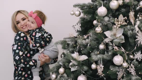 Festive Mother and Infant Daughter Decorating Christmas Tree at Home