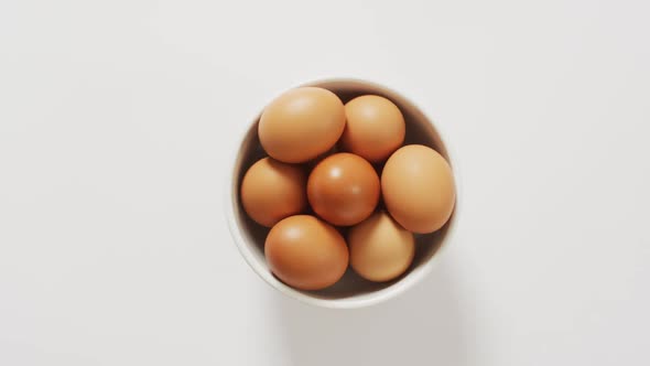 Close up of bowl of brown eggs with copy space on white surface