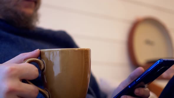 Closeup of Coffee Mug and Smartphone in Hands