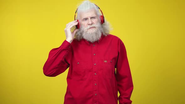 Middle Shot Portrait of Senior Caucasian Man Putting on Headphones and Searching for Romantic Song