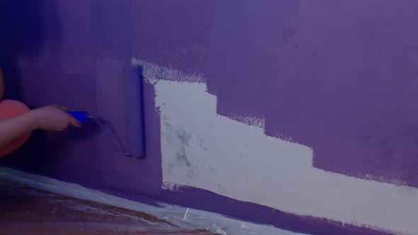 Close Up of Woman's Hand in Protective Glove Painting Wall in Purple Colour with Roller