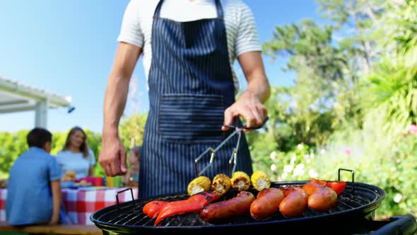 Man flipping bell pepper on barbecue