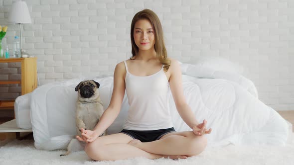 Asian woman practice yoga lotus pose with dog pug breed enjoy and relax with yoga