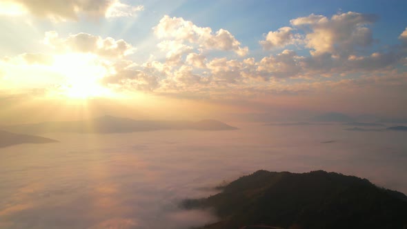 The rays of the sun shine through the clouds into the misty sea above the mountains in the morning