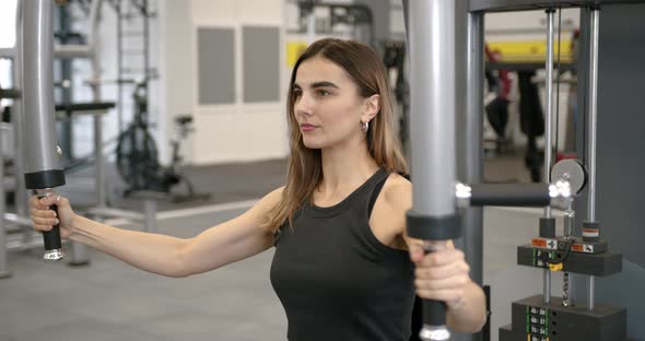 Young Woman Performs an Exercise in a Butterfly Simulator