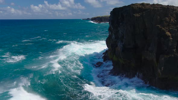 Aerial Top View of Waves Break on Rocks in a Blue Ocean