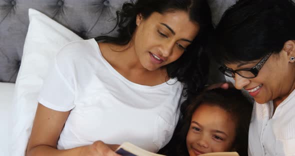 Multi-generation family reading a book in bedroom 4k