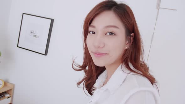 Asian woman with white shirt talking to selfie video call walk to bed with a smile