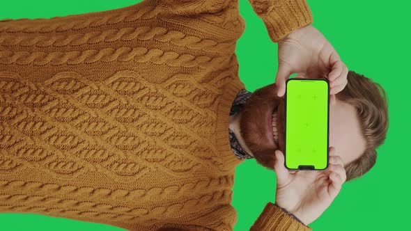 Vertical Shot Bearded Caucasian Man Covering His Eyes with Greenscreen Smartphone Over Green