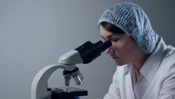 Woman Tired of Looking Through Microscope at Workplace