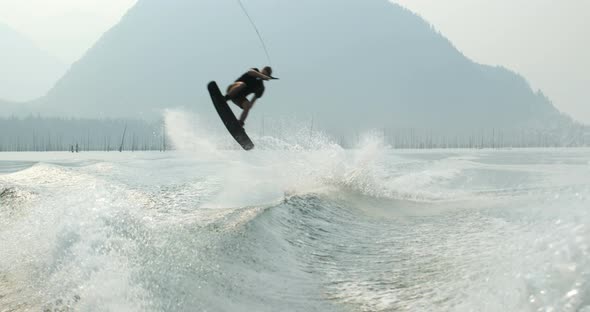 Front view of caucasian young man doing tricks on wakeboard in the city river 4k